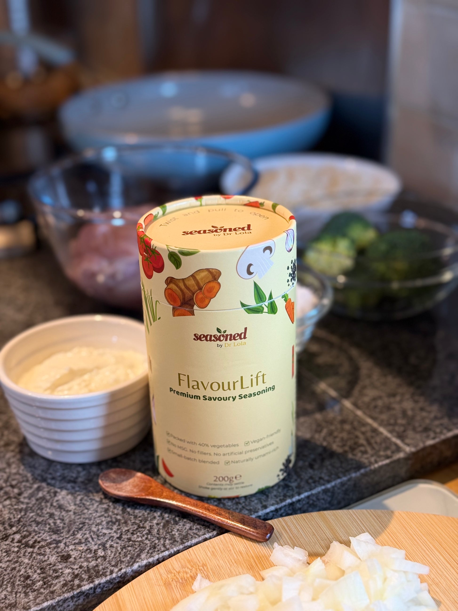 FlavourLift premium savoury seasoning container on a kitchen counter with ingredients in the background